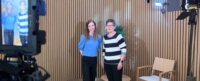 Anna-Elina Rahikainen and Dr. Päivi Lähteenmäki smiling on a filming set with cameras and studio lights during a session for the e-QuoL project at Siltasairaala (Bridge Hospital), HUS Helsinki University Hospital.
